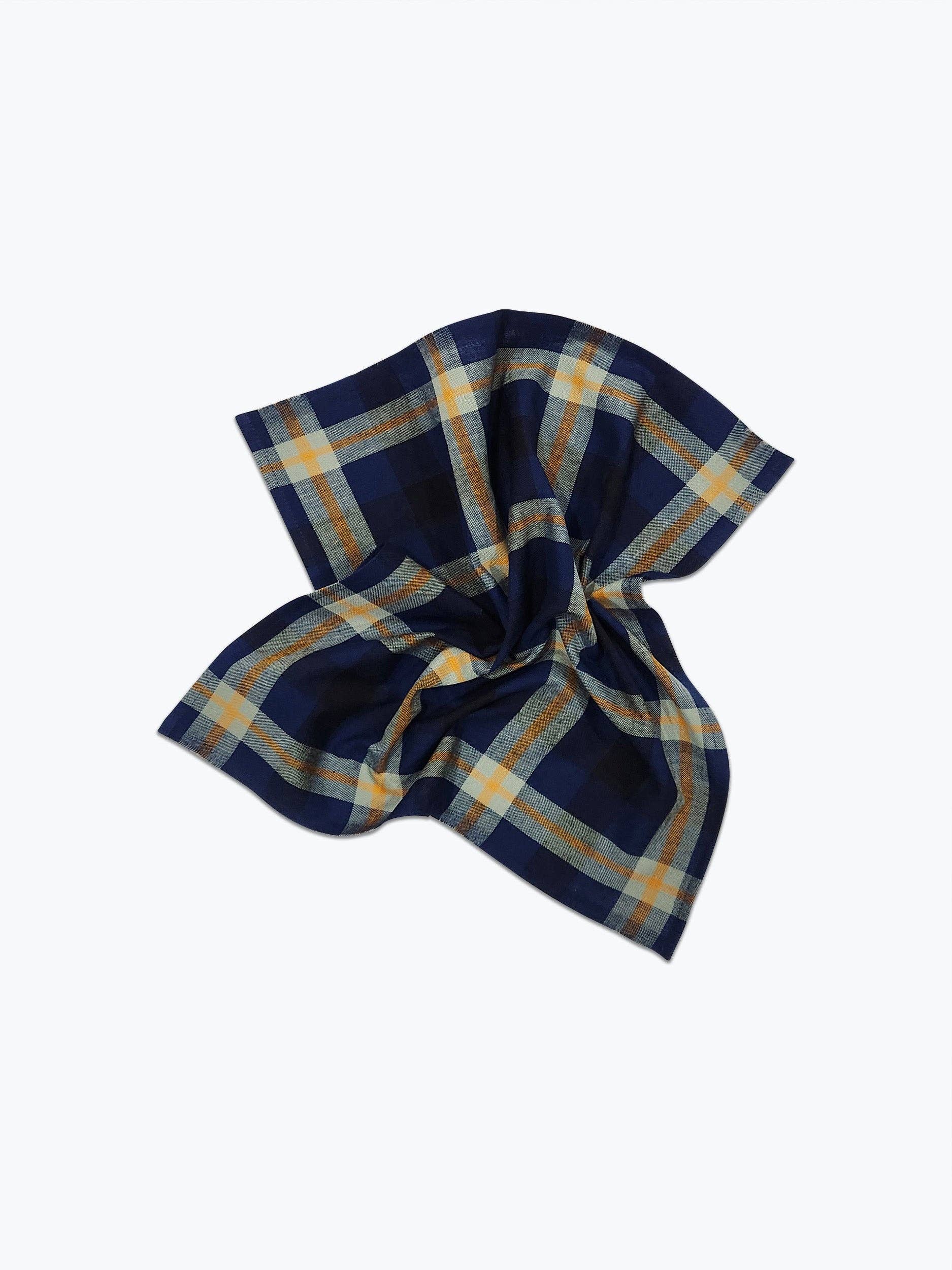 A scrunched handwoven plaid napkin with blue, yellow, and brown colors displayed on a white background.