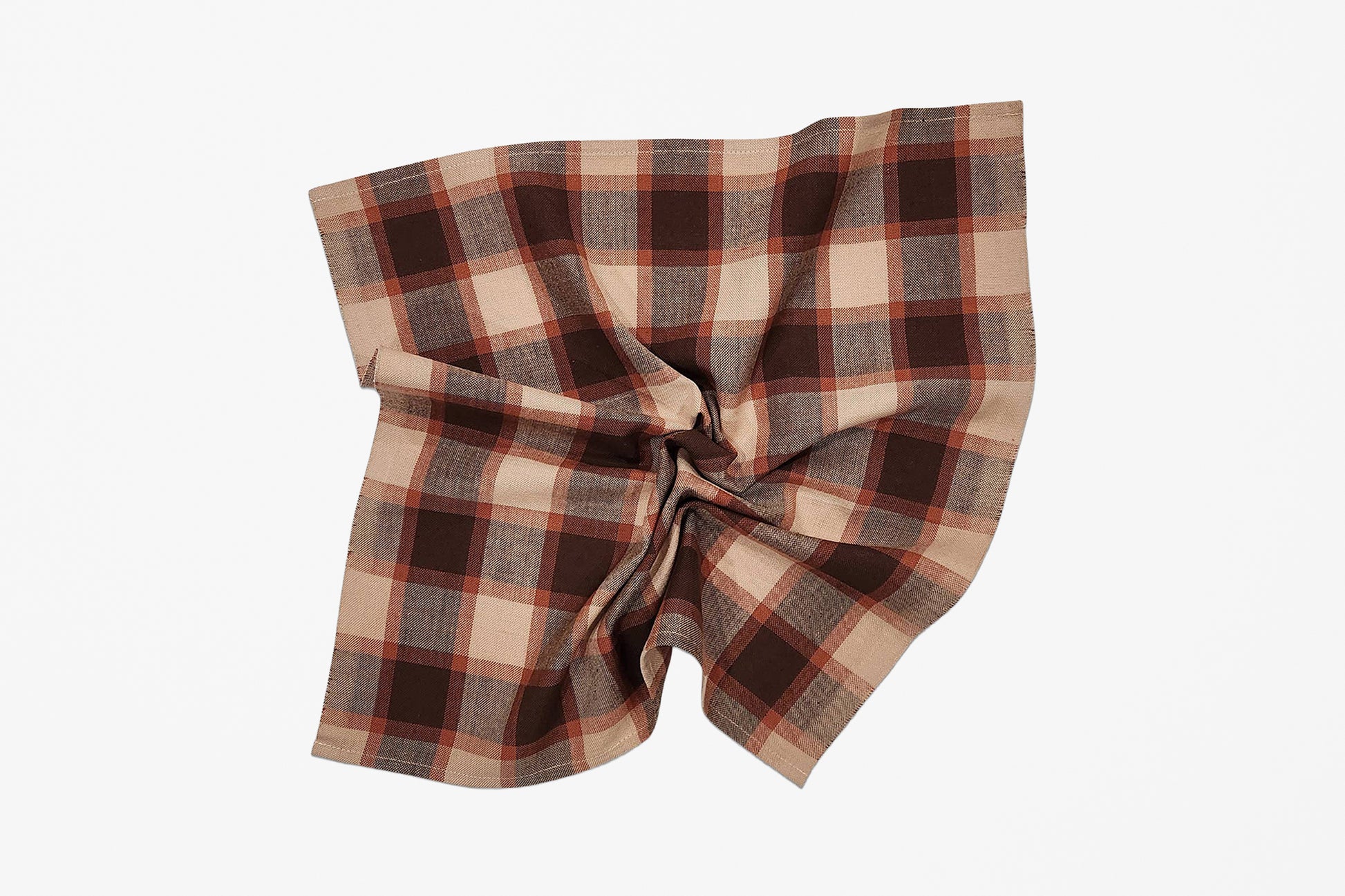 A scrunched square plaid napkin in beige, brown, and rust red tones, styled with a gathered twist on a plain white background.