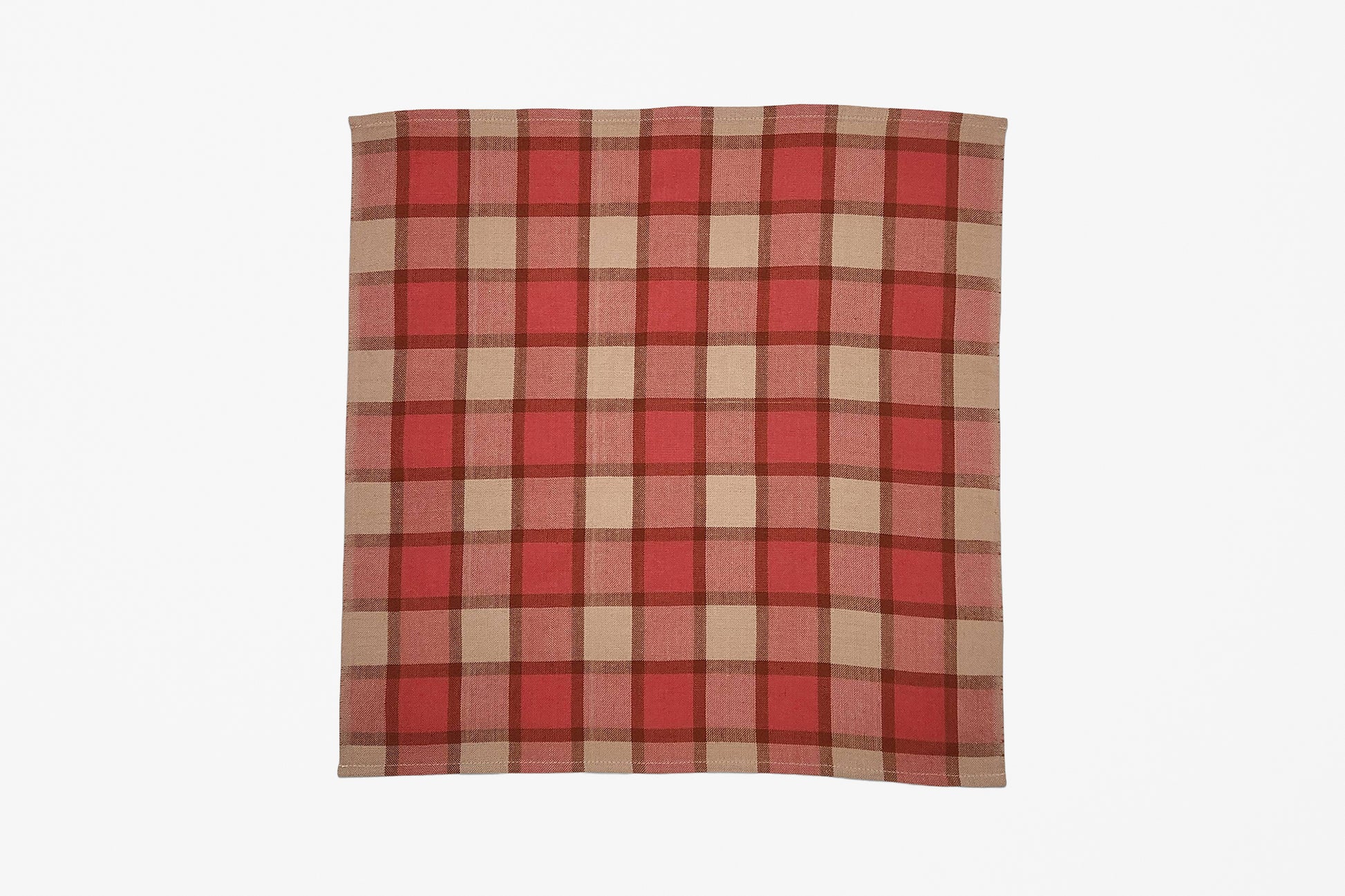 A square woven plaid napkin with a red, pink, and beige plaid pattern, displayed flat against a solid white background.