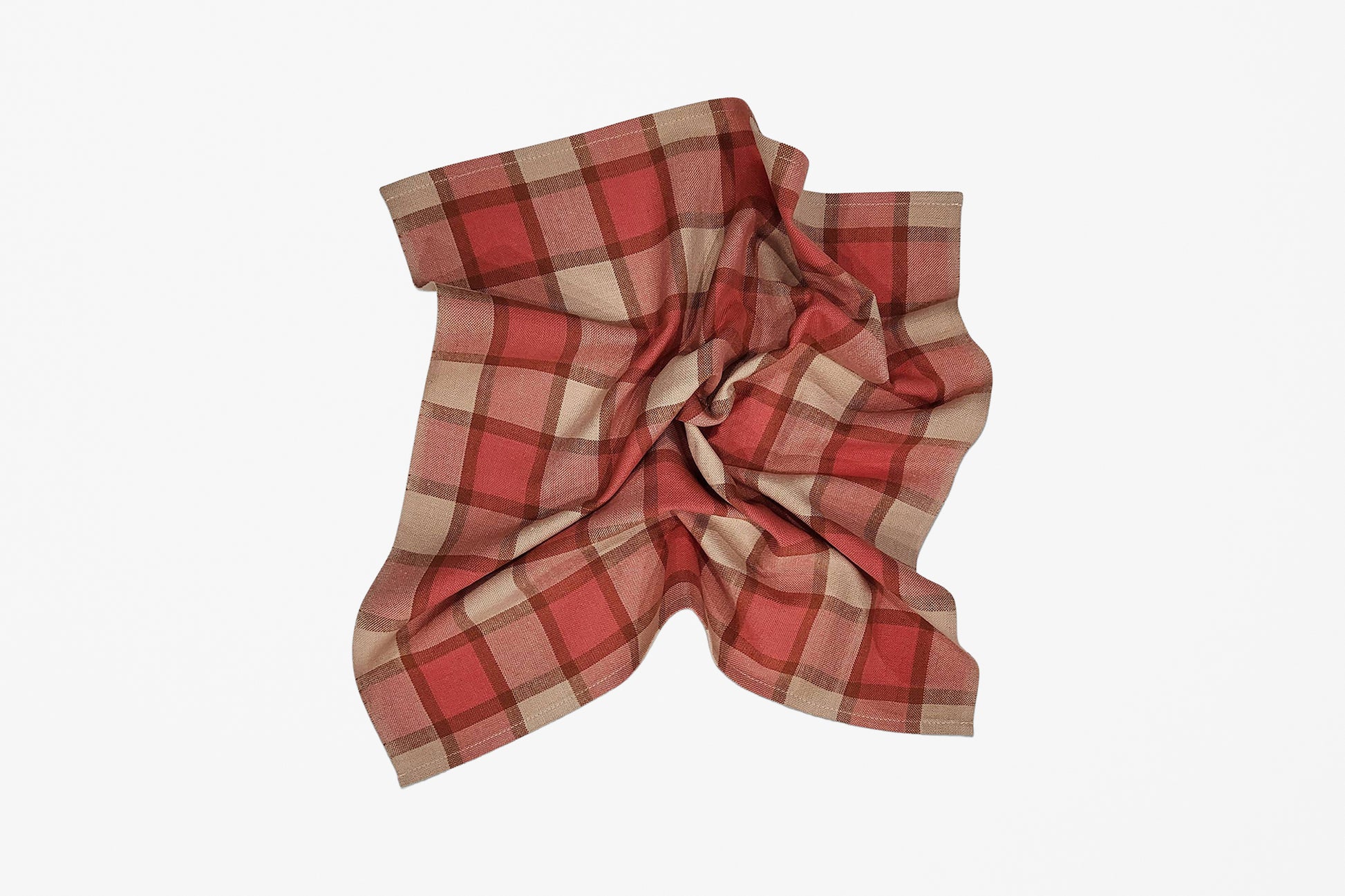 A scrunched plaid napkin in red, pink, and beige, styled against a plain white background.