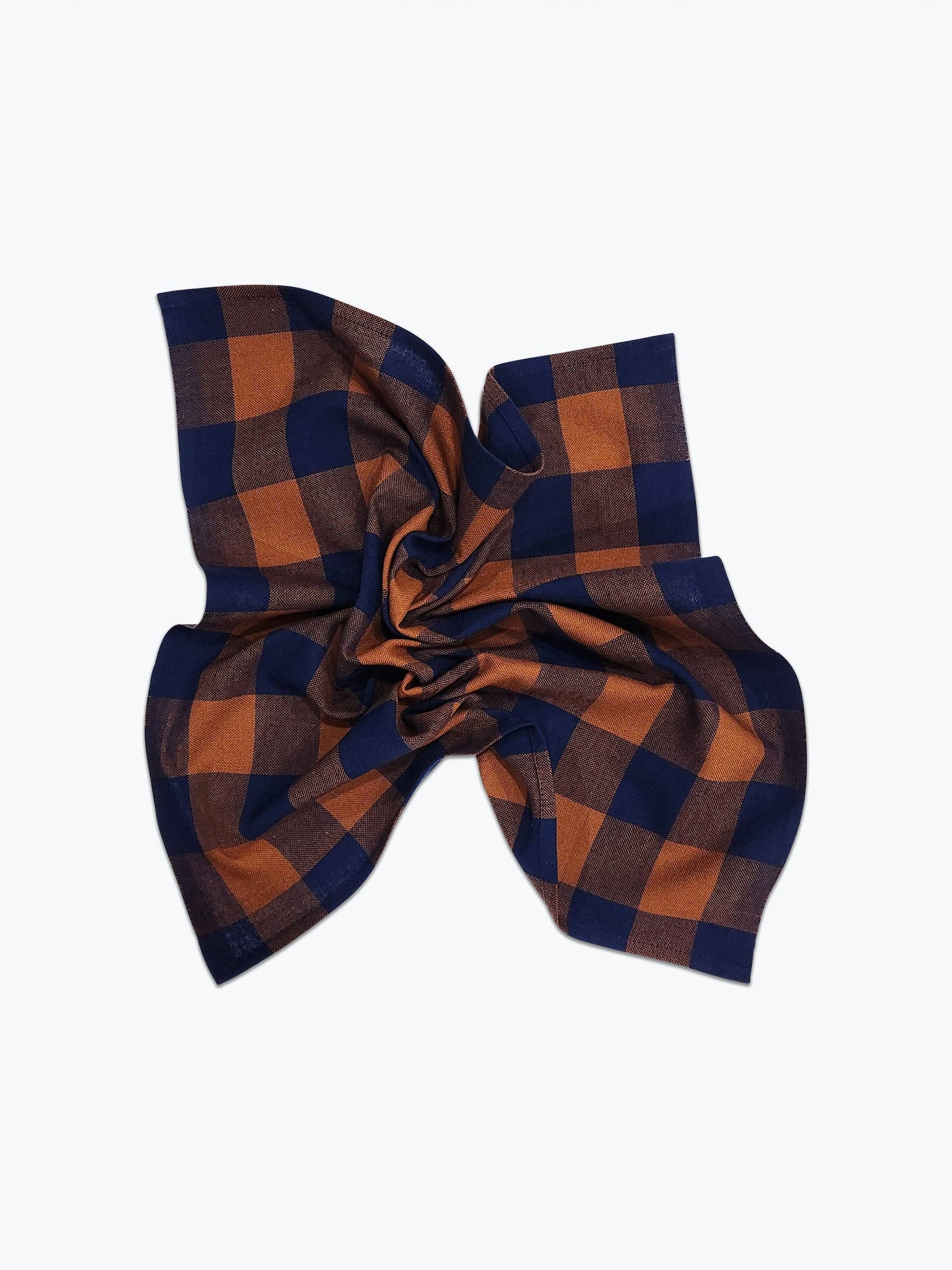 A scrunched handwoven gingham plaid napkin with blue and orange pattern on a white background. 