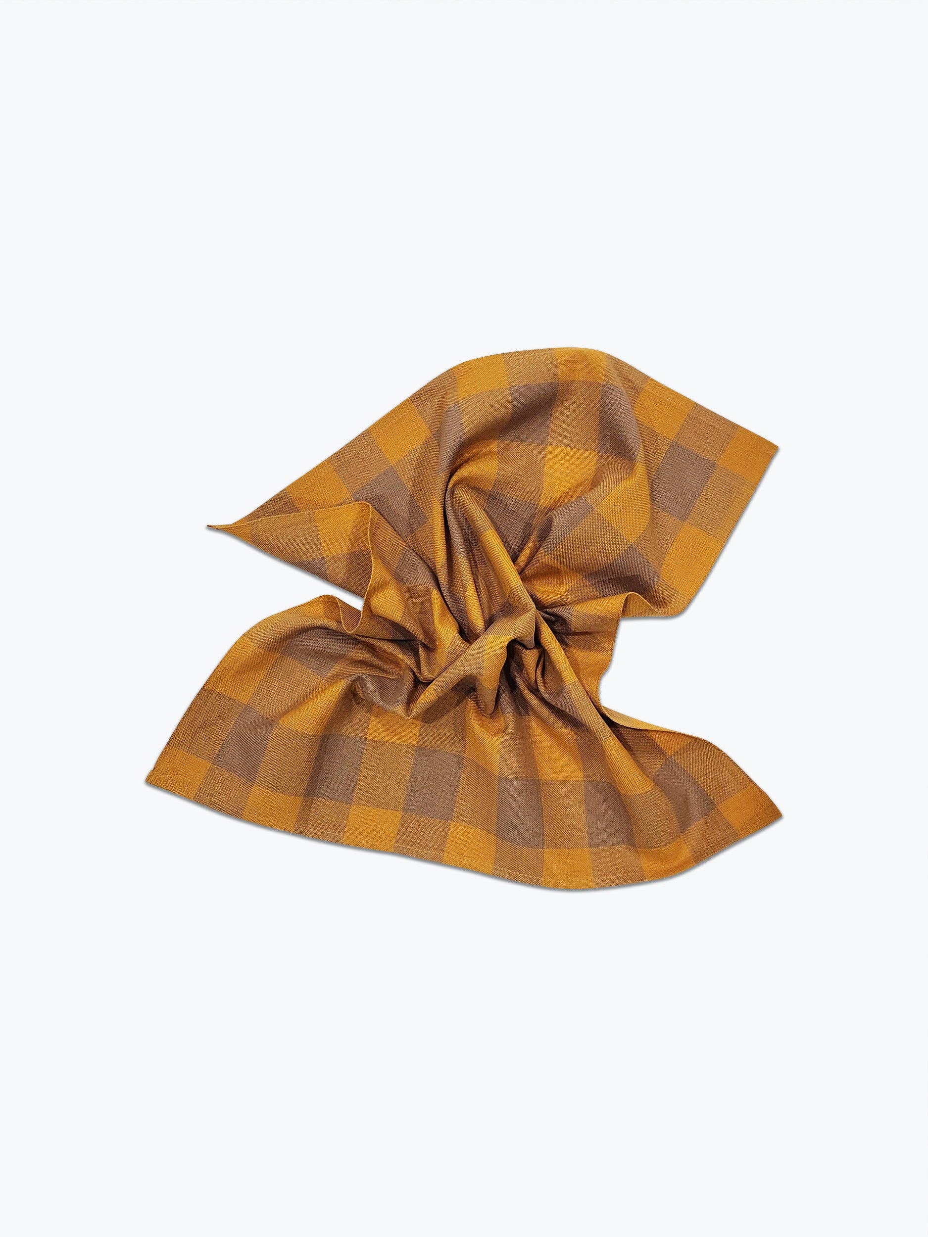 A handwoven gingham napkin with orange and brown pattern displayed on a white background.