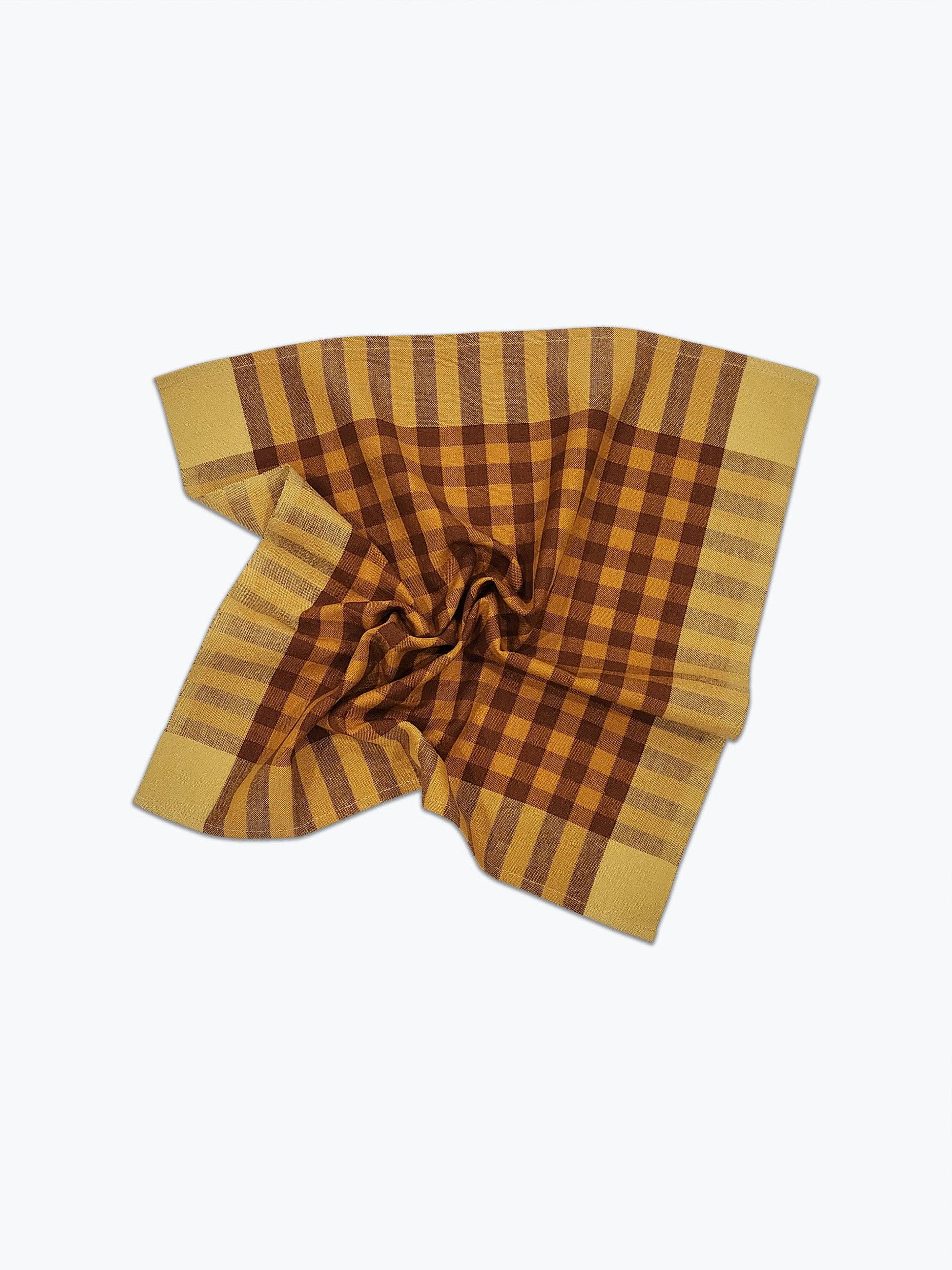 A handwoven plaid napkin with brown and yellow pattern on a white background.