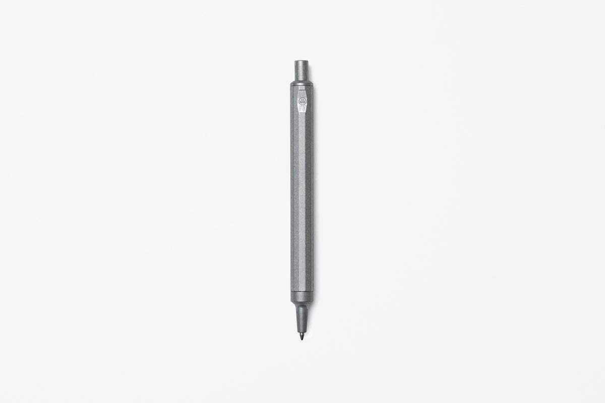 A sleek, raw aluminum pen centered vertically on a clean, solid off-white background.
