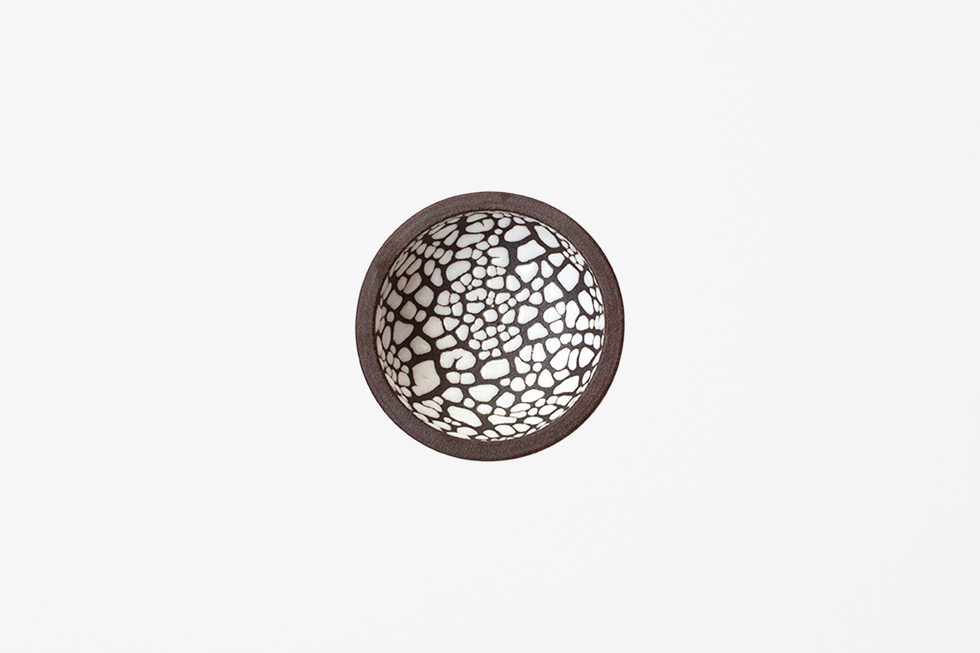 A round ceramic bowl viewed from directly above, featuring a dark brown rim and glossy white crackle mosaic pattern inside.