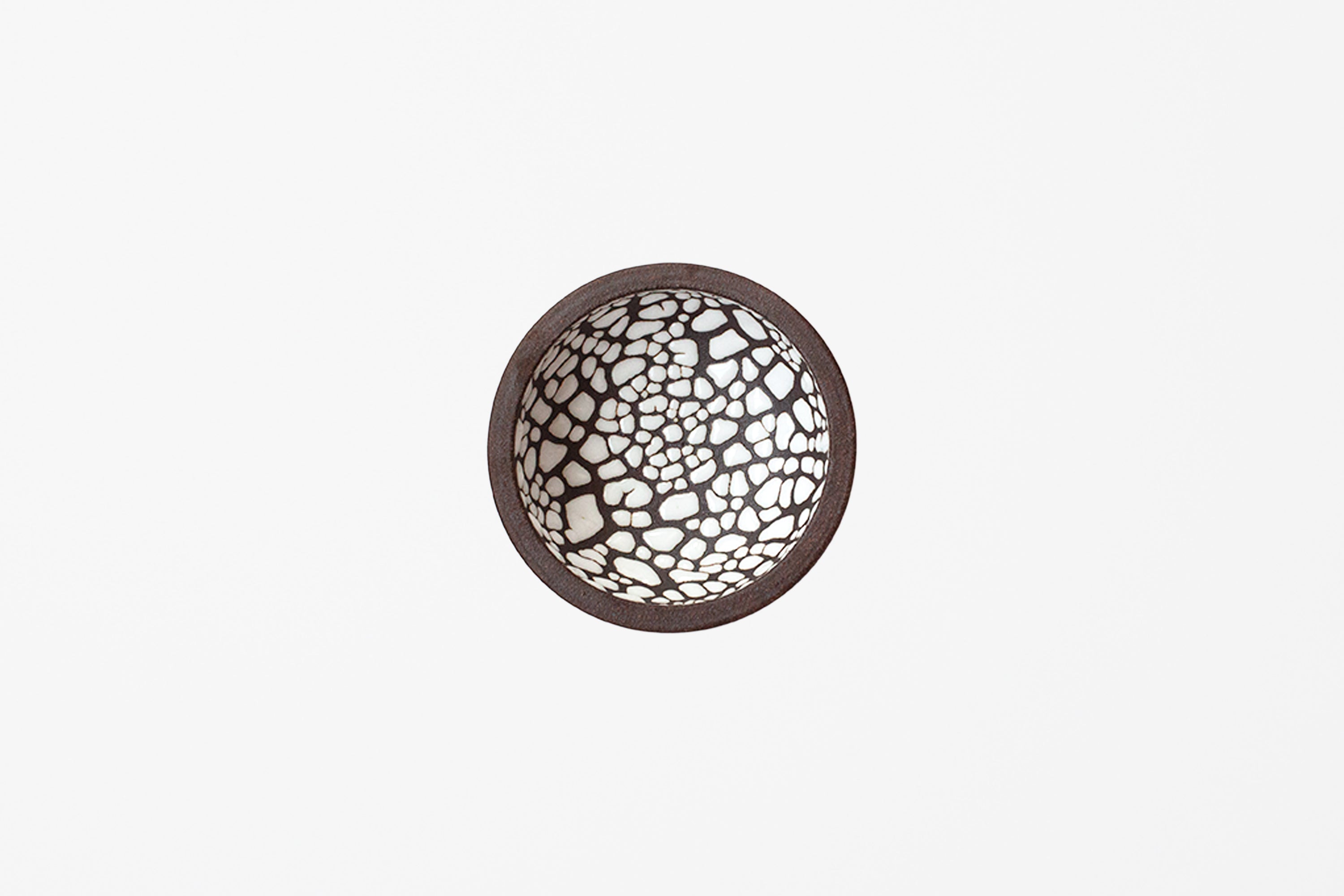 A round ceramic bowl viewed from directly above, featuring a dark brown rim and glossy white crackle mosaic pattern inside.