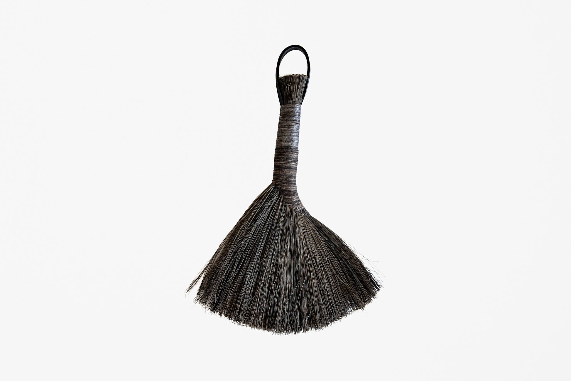A traditional Apalachian hand brush with a dark brown to black bristle head, a wrapped handle, and a hanging loop, shown against a plain white background.