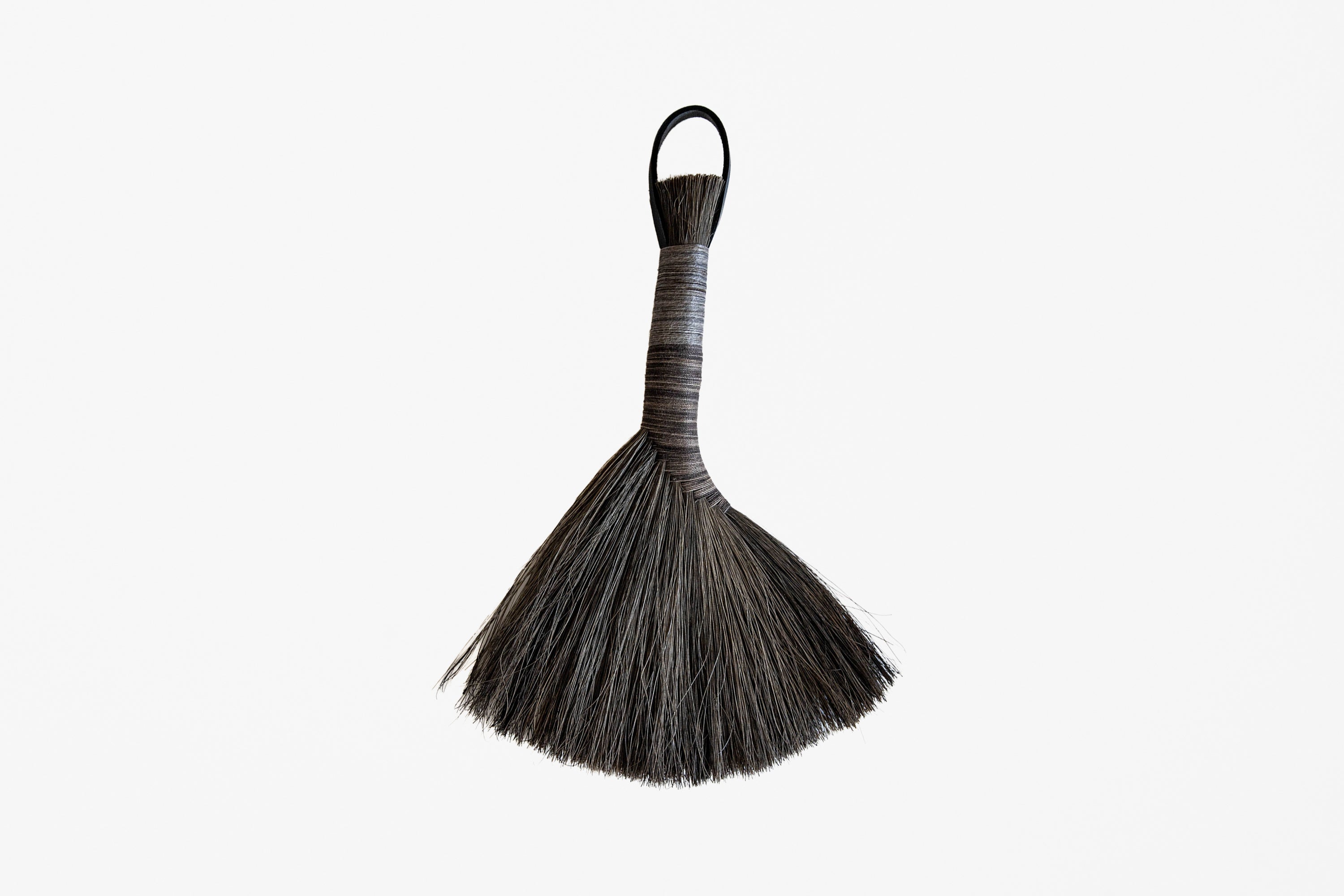 A traditional Apalachian hand brush with a dark brown to black bristle head, a wrapped handle, and a hanging loop, shown against a plain white background.