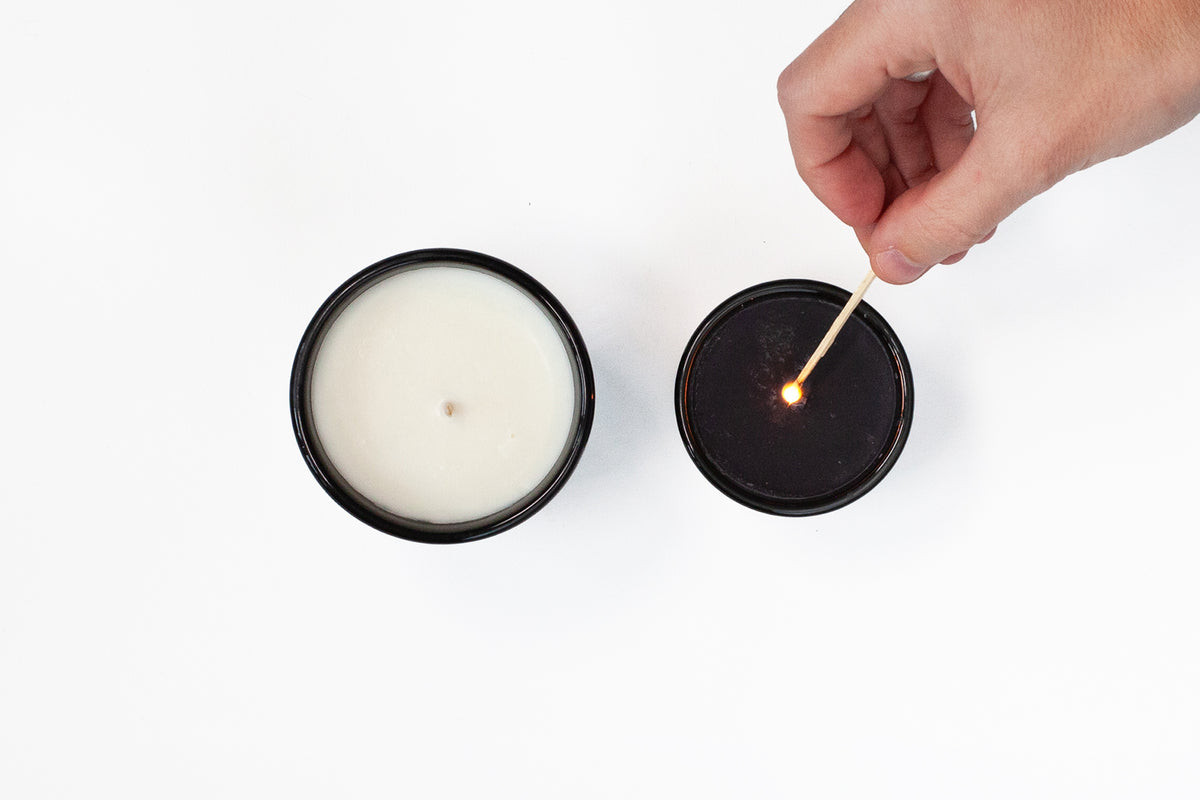 Hand lighting a candle with a match on a white background